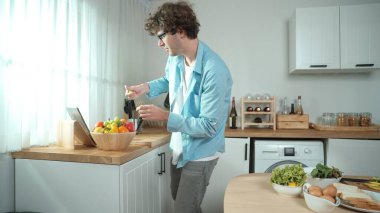 Mutlu baba yemek pişirirken müziğe geçiyor ve modern mutfakta öğle yemeği hazırlıyor. Aktif baba, sebze ve mutfak gereçleri ile çevrili sağlıklı yemek ya da salata yaparken şarkıyla dans ediyor. Pedagoji.