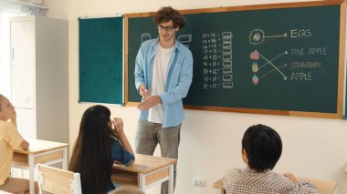 Attractive girl raised his hand and volunteer to write answer on blackboard. Teacher ask for volunteering to answer question while skilled student receive chalk and walk in front of class. Pedagogy.
