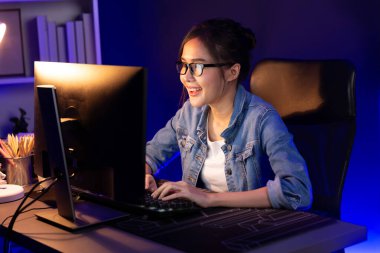 Gülümseyen genç Asyalı yaratıcı memur internette satış hedefine bakıyor. Neon lambası gecesinde yeni strateji pazarlaması planlamak için serbest iş sahibi oluyor. Taktik.