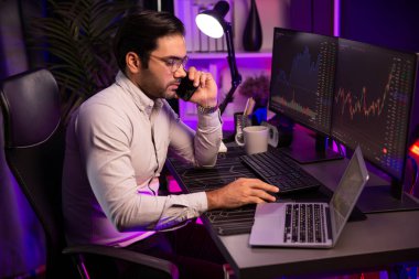 Tüccar akıllı işadamı komisyoncuyu ya da ortağını arıyor, modern evde kârlı bir finans teknolojisi olan neon aydınlatma ofisindeki bilgisayardaki dinamik borsa yatırımlarını analiz ediyor. Tahmin et..