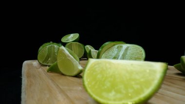 Yakın plan, canlı bir dilim taze kireç kırsal bir ahşap kesme tahtasının üzerinde duruyor. Tazelik ve canlılık yayıyor. Kesme tahtasına konmuş yeşil limon diliminin yarı saydam zarları. Geliştirilebilir.