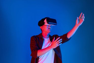 VR gözlüklerinden bakan zeki Asyalı adam, yenilikçi teknolojide dokunmatik ekran ile 3D hologram meta arayüzünü analiz ederek metazıt doğrultuda araştırma dizini verilerine dönüyor. Entrika.