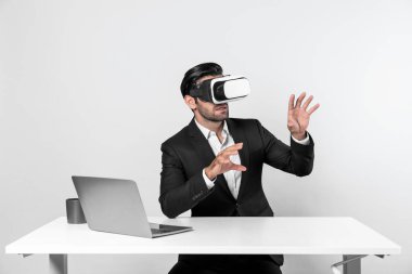 Bilgisayarla masada otururken ve VR gözlüğü takarken veri analizine bakan yetenekli bir iş adamı. Proje yöneticisi sanal gerçeklik sistemini kullanarak ya da metaevrende bağlantı kurarak çalışıyor. Sapma.