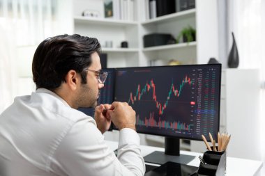 Akıllı tüccar işadamı, modern merkez ofisindeki araştırma pazarında en yüksek kârlı finansal teknolojiye yatırım yaparak bilgisayar üzerinde iki dinamik borsa yatırım ekranını analiz ediyor. Tahmin et..