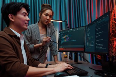 Bilgi teknolojisi geliştiricileri modern ofisteki neon ışık odasında verileri çevrimiçi olarak çalıştıran akıllı web sitesi geliştirme kodlayıcı sistemine işaret ediyorlar. İnfobahn.