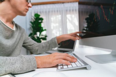 Bilgisayar ve dizüstü bilgisayarı kullanarak, çalışma masasındaki dinamik artırılmış borsa grafiğinin en yüksek kar değerini araştıran bir tüccar, modern ofisteki ekrandaki döviz kuru değerini analiz ediyor. Bireysel.