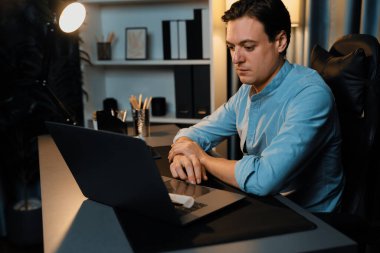 Akıllı iş adamı, gece vakti mavi perde arkasında iş hedefi olan finansal teknoloji veri raporlarını analiz etmek için veritabanı stoklarını araştırmak üzere dizüstü bilgisayarda uzaktan çalışıyor. Bireysel.