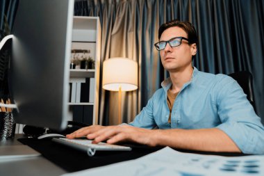 Akıllı iş adamı iş paragrafı dinamik pazarlama analizi planını analiz ediyor. Kağıt kağıtları ve bilgisayar monitörü raporlarını gece evdeki belge verileriyle karşılaştırmak için hazırlıyor. Bireysel.