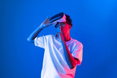 Sanal gerçeklik dünyasını dijital fütüristik teknolojiye bağlayan mavi pembe ışık duvarını gösteren 3 boyutlu hologram gösteren genç bir Afro-Amerikan oyun oyuncusu. Entrika.