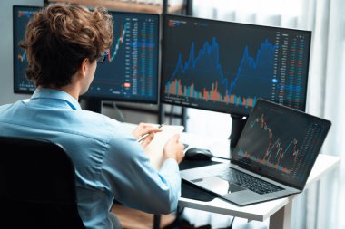 Piyasa stoku grafiği üzerinde çalışan genç profesyonel tüccar ev ofisindeki gerçek zamanlı ekranlara yatırım yaparak önemli döviz kuru kavramları yazarak analiz ediyor. Toplayıcı.