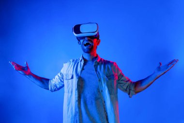 VR gözlük takan gülümseyen adam sanal gerçeklik dünyasına giriyor. Beyaz ergen, ekipman kullanarak siber uzay gelecekteki yenilikçi teknoloji simülasyonuna bakarken heyecanlanıyor. Sapma.