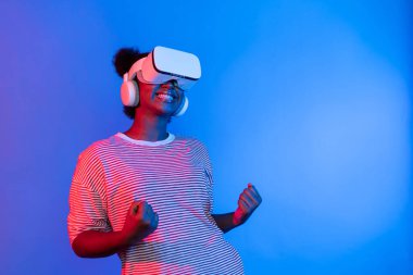 VR 'ı olan genç Afrikalı bir kadın, kazanmak için metaevrensel oyun oynamaya başlıyor. Neon Stüdyo ışıklarını 3D teknoloji yenilik teknolojisi uygulama kullanıcısı deneyimi için yumrukluyor. Entrika.