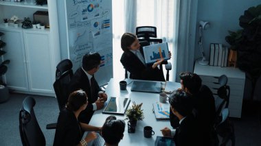 Akıllı iş kadınlarının en üst görüşü çeşitli iş adamlarına satış tablosunun arttığını gösterirken, bir grup farklı iş adamı da masada belgelerle hisse yatırım verilerini dinleyip analiz ediyor. Müdürlük.