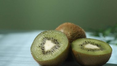 Islak zeminde dilimlenmiş kivi meyvesi ve yeşil arka planda yakın plan. Makro taze kivi ve su dalgalı dilimlenmiş kivi. Sağlıklı beslenme ve doğal gıda kavramı. Poster için tasarım, duvar kağıdı. Pabulum.