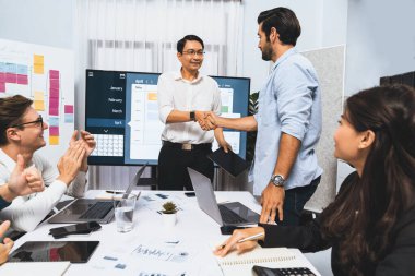 Mutlu ofis çalışanı ve proje yöneticisi, zamanında ve zamanında başarılı bir iş başardıktan sonra toplantı odasında el sıkışıyor. İş için proje yönetimi izleme yazılımı başarılı.