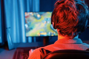 Savaş arenasında çoklu oyunlar takımıyla Moba 'da savaşan genç oyun flamasının sunucu kanalı, neon dijital ışık modern odasındaki arka görüntü ile bilgisayar monitöründe kulaklık takıyor. Toplayıcı.