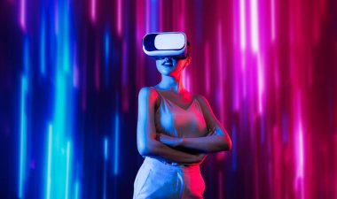 Zeki bir kadın, metaevreni birbirine bağlayan VR kulaklık takan neon ışıklarla çevrili duruyor. Gelecekteki siber uzay topluluğu teknolojisi. Zarif kadın kendinden emin bir şekilde çapraz kol pozu veriyor. Uzağa bak. Halüsinasyon.