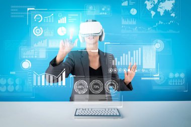 Proje yöneticisi mali grafiği kontrol etmek için görsel gerçeklik gözlüğü takıyor. VR kulaklık takıp klavyeli masada otururken veri analizine işaret eden yetenekli bir iş kadını. Kısıtlanma.