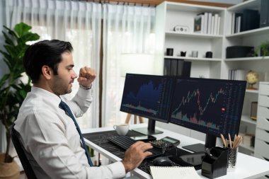 İki borsa yatırım ekranı olan tüccar işadamında başarılı olmak, çalışma masasında yüksek kar elde etmek için yumruğunu kaldırmak, ofisteki borsada dinamik teknoloji grafiği. Tahmin et..