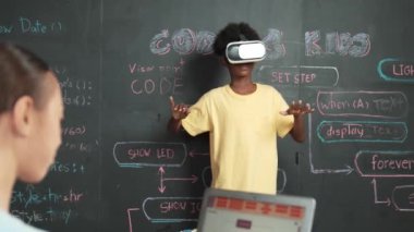 Genç bir kadın kameraya, kodlamaya ya da programlama sistemine bakarken Afrikalı çocuk VR gözlük kullanıyor. Akıllı ergen, STEM sınıfındaki programa dokunurken tahtada duruyor. Öğretim