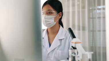 Laboratuvar kimya araştırmacısı mikroskop ve dizüstü bilgisayar kullanarak yeni ilaç ya da tedavi geliştirir. Bilimsel uzmanlığa ve laboratuvar mikrobiyoloji ekipmanlarına sahip sağlık teknolojisi. Ağır çekim. Katı.