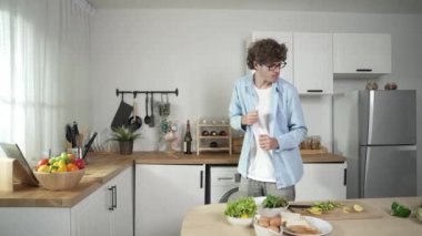 Mutlu baba yemek pişirirken müziğe geçiyor ve modern mutfakta öğle yemeği hazırlıyor. Aktif baba, sebze ve mutfak gereçleri ile çevrili sağlıklı yemek ya da salata yaparken şarkıyla dans ediyor. Pedagoji.