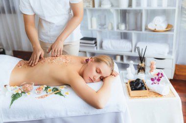 Lüks spa salonlarında sıcak mum ışığında cilt bakımı yaptıran kadın müşteri. Sağlık Spa vücut fırçasında tuz temizleme güzellik tedavisi. Sessiz.