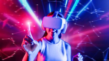 Zeki bir kadın, metaevreni birbirine bağlayan VR kulaklık takan neon ışıklarla çevrili duruyor. Gelecekteki siber uzay topluluğu teknolojisi. Sanal objeye parmağını kullanan zarif bir kadın. Halüsinasyon.