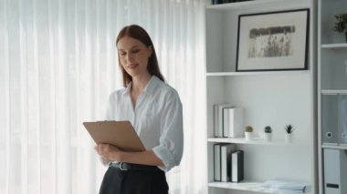 Klinikteki dost canlısı psikolog kadın. Profesyonel portresi. Kameraya bakıp psikolog muayenehanesine bakıyor. Tecrübeli ve kendinden emin psikolog.