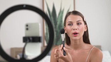 Sosyal medya için güzellik ve kozmetik video içeriği hazırlayan genç bir kadın. Güzellik blogcusu kameraya gülümserken seyircilere ve takipçilere güzellik bakımını gösteriyor. Düzenle