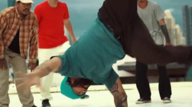 Profesyonel Asyalı sokak dansçısı çatıda çok kültürlü arkadaşlar dans ederken B boy dansı yapıyor. Genç modern dans grubu hip hop hareketi yapıyor. Tarz, moda, aksiyon. Açık hava sporu 2024 hiphop..