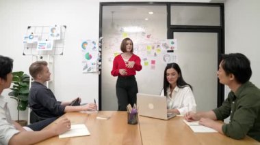 Genç liderin kapanışı, proje hakkında beyin fırtınası yapan meslektaşı ve proje yöneticisi tarafından çevrelenmiş zihin haritası ve renkli yapışkan notlar kullanılarak kendinden emin bir şekilde iş projesini sunuyor. Tertemiz..