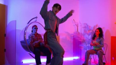 Çok kültürlü bir arkadaş kürsüde otururken Asyalı yetenekli bir dansçı modern müziğe geçiyor. Profesyonel dansçı, hipster takımı tezahürat yaparken ve desteklerken enerjik adımlar atıyor. Mutluluk.