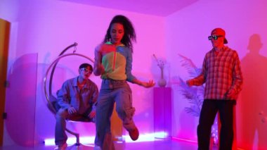 İspanyol hipster renkli kıyafetler giyer ve serbest stil müziğe el sallar. Profesyonel break dansçı neon ışıklarıyla ve modern stüdyo arkadaşlarıyla coşkuyla dans ediyor. Mutluluk.