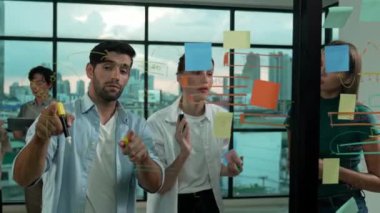 Mutlu iş adamları cam duvarı işaret ederken kendilerine güveniyorlar. İş adamlarından oluşan bir grup, şeffaf yönetim kurulunda iş fikri, strateji ve planlama ile ayakta duruyor. İzleme