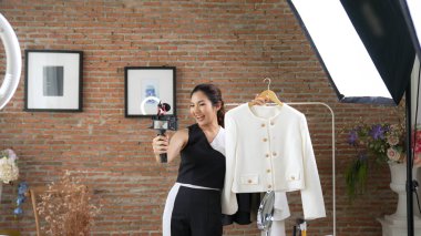 Kadın nüfuzlu kişi video görüntülerini canlı yayınlıyor. Sosyal medya ya da blog. Stüdyo ışıklandırması olan mutlu genç bir kız pazarlama için internet üzerinden yayın yapıyor..