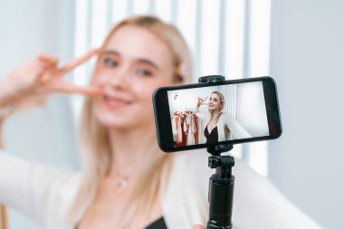 Genç sosyal medyum kadın moda videosu yapıyor. Blogcu gülümseyip telefon çubuğu selfie 'si kullanırken aynı zamanda ikna edici online giysiler izleyicilere ya da takipçilere vlog sattırıyor. Blithe