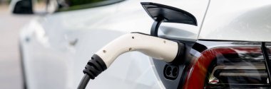 Panorama afişi EV elektrikli araç ulusal parktaki ya da dışarıdaki EV şarj istasyonundan şarj oluyor. Çevre dostu EV arabalarla yaz ormanlarında doğal koruma. Yükselt