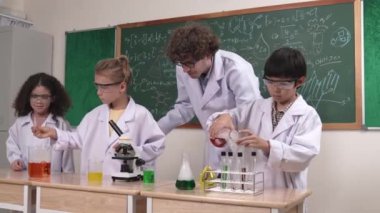 Kafkasyalı zeki öğretmen, meraklı öğrencilerin laboratuardaki deney kabına renkli sıvı dökmesini destekler. Yaratıcı çocuklar deney yapmaya ve biyokimyasal örnekleri incelemeye konsantre olurlar. Pedagoji.