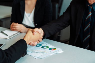 İş adamları konsepti kabul ediyor. İş adamı ve Asyalı iş kadını ofiste el sıkışırlar. uds