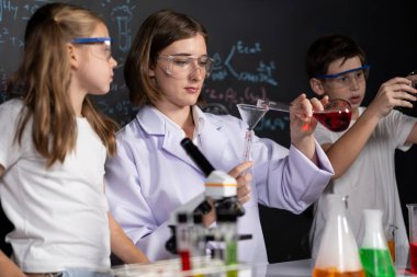 Laboratuvarda çalışan öğretmen, güvenlik gözlüğü takıyor, STEM sınıfında kimya bilimi üzerine deney yapıyor. Öğrenci komedisi tüpte sıvı deneyi yapar. Etkinlik.