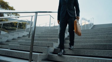 Becerikli bir yöneticinin elinde bir çantayla merdivenlerden inip evine dönmesi. Proje yöneticisinin bacağı kovulacak ve yurda yürüyecek. Dağınık takım elbiseli bir yatırımcı. Bacağa odaklan. Sevinçli..