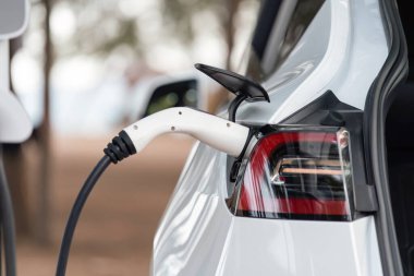 Kapalı EV şarj kolu fişe takıldı veya elektrikli arabaya bağlandı, EV araba aküsünü temiz çevre için sıfır CO2 emisyonu ile alternatif ve sürdürülebilir enerjiyle şarj etti. Kalıcı
