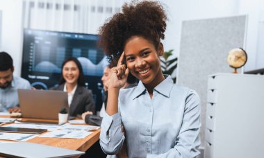 Bir grup ofis çalışanı ile birlikte arka planda ekranda gösterim paneliyle buluşan mutlu Afrikalı genç bir iş kadını portresi. Takım toplantısında kendine güveni tam bir ofis hanımı. Uyum