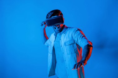 Kafkasyalı bir adam VR cam takıyor ve hareket eden el kol kılıcını tutuyor. Oyuncu, gelecekteki sanal gerçeklik kulaklığını ya da gelecekteki yenilikleri kullanarak meta dünyaya giriyor ya da aksiyon oyunu oynuyor. Sapma.