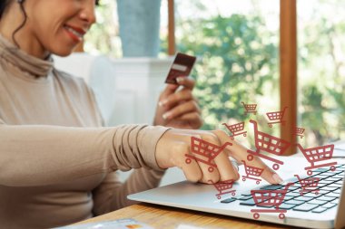 Kahverengi kazak giyen, elinde kredi kartı yazılı dizüstü bilgisayarı olan şık bir müşteri online platform seçiyor. Akıllı tüketici e-ticaret uygulaması açıyor. Nakitsiz teknoloji alışveriş envanteri kullanıyor. Siber Nakit.
