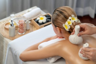 Sıcak bitkisel top spa masaj vücut tedavisi, masör kadın vücuduna nazikçe şifalı bitki torbası bastırıyor. Aromaterapi dinlenme sükuneti ve sükuneti kaplıca salonundaki atmosferi aydınlatıyor. Sessiz.