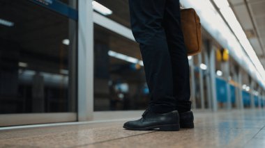 Çantayı tutarken ayakta duran ya da treni bekleyen yetenekli beyaz iş adamı. Kapıda duran akıllı proje yöneticisinin bacağının yakın çekimi. Toplu taşımayı temsil eden, bekleyen, yöneten. Sevinçli..
