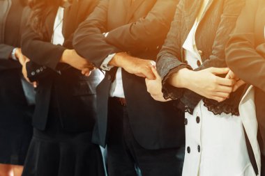 Birçok mutlu iş adamı neşe ve başarıyla el ele tutuşuyor. Şirket çalışanı başarılı bir iş projesini bitirdikten sonra kutlama yapıyor. Şirket ortaklığı ve başarı kavramı. uds