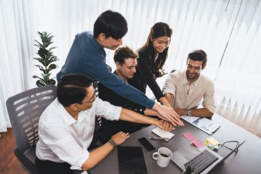 Çeşitli ofis çalışanlarından oluşan bir grup, ofis odasında el ele vererek iş sinerjisini ve iş yerindeki güçlü verimli takım çalışmasını sembolize ediyor. İş çalışanları arasındaki işbirliği ve birlik. Tedbirli